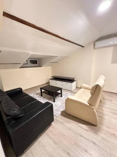 a living room with a black couch and a table at Appartement entier full équipé in Charleroi
