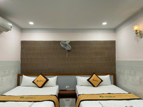 a bedroom with two beds and a fan on the wall at hotel Hương Thiên Phú in Dĩ An