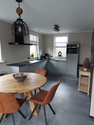 a kitchen with a wooden table and chairs in it at Vakantiewoning Nimmerdor, Grijpskerke, dichtbij strand en stad in Grijpskerke