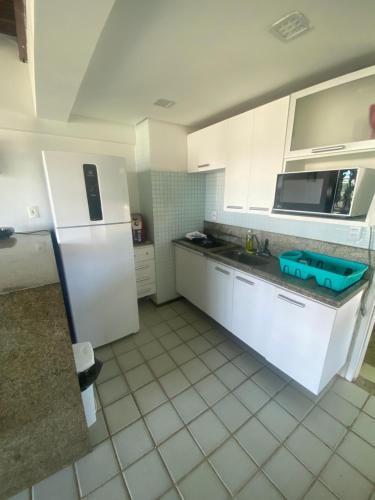 eine Küche mit weißen Schränken und einem weißen Kühlschrank in der Unterkunft Ancorar Flat - dois quartos in Porto De Galinhas