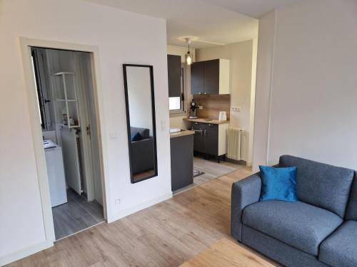 ein Wohnzimmer mit einem blauen Sofa und einem Spiegel in der Unterkunft Appartement traversant ensoleillé in Boulogne-Billancourt