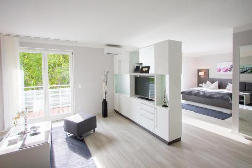 a large white room with a bed and a television at ApartHotel "Am Fließ" in Hoyerswerda