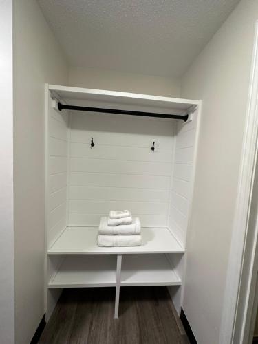 a white closet with three towels on a shelf at Green Harbor Hotel in Marshfield