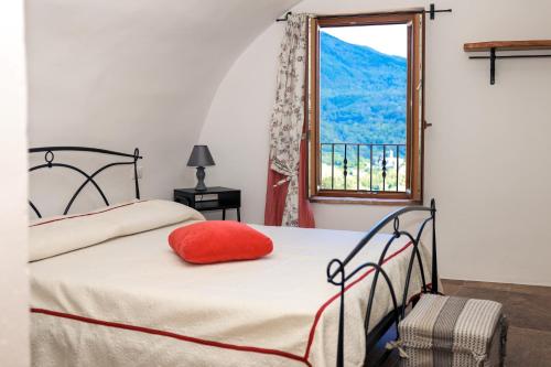 a bedroom with a bed with a red pillow and a window at Ca'Toni in Bagnone
