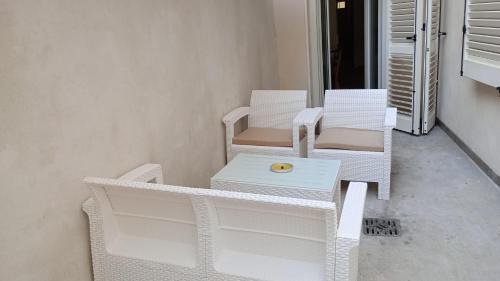 Dos sillas blancas de mimbre y una mesa en un porche. en LOFT CON CORTILE, en Forlì