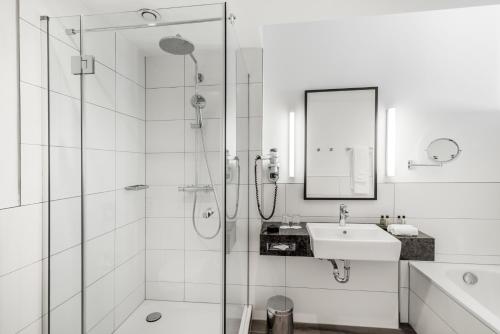 
a bathroom with a shower, sink, and mirror at Bilderberg Parkhotel Rotterdam in Rotterdam
