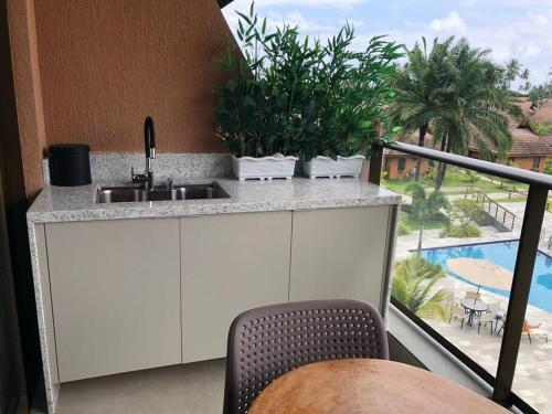 Il dispose d'une cuisine avec un évier et d'un balcon avec une piscine. dans l'établissement Eco Resort Praia Dos Carneiros - Flat Praia, à Tamandaré
