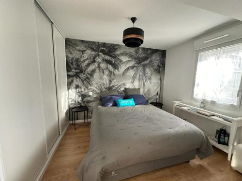 een slaapkamer met een bed met een muurschildering van palmbomen bij Arradon Golfe du Morbihan Appartement 2 Pièces plain-pied Terrasse in Arradon