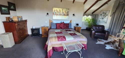 een slaapkamer met een bed, een stoel en een dressoir bij MnM's BnB in Napier