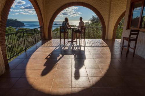 a man and woman sitting at a table on a balcony at Beachside stay at Villa ViYarte in San Juan del Sur