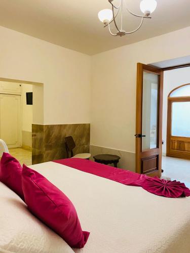 a bedroom with a large white bed with red pillows at Mansión Leonor in Bernal
