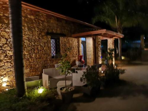 een stenen huis met een tafel ervoor 's nachts bij Villa Oleandra Relais in Partinico
