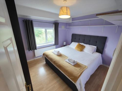 a purple bedroom with a bed with towels on it at Entire 3 bed house/free private parking, garden in Falmer