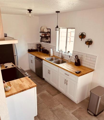 a kitchen with white cabinets and a sink at Adobe Hideaway House in Joshua Tree