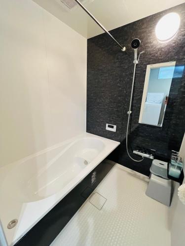a bathroom with a white bath tub and a sink at 村の小さなお宿　おきな in Tosa
