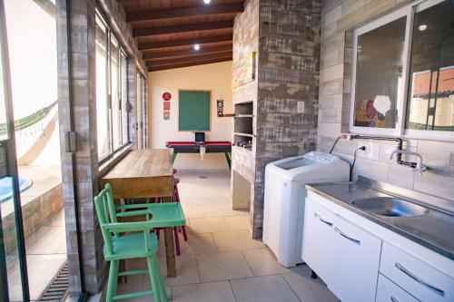 a kitchen with a sink and a washing machine at Casa 3 min Shopping Pelotas- Com 1 Suíte, 2 Quartos Climatizados, Piscina e Estacionamento 2 carros in Pelotas