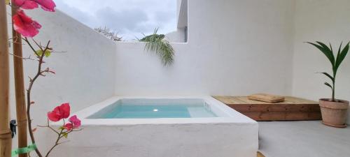 une baignoire dans une pièce blanche avec des fleurs dans l'établissement xenónas appartement avec petite piscine privée, au Grau-dʼAgde