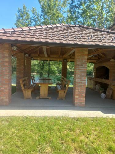 a wooden pavilion with a table and a picnic table at Drinsko Srce in Ljubovija