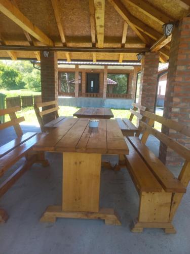 a wooden picnic table with benches in a pavilion at Drinsko Srce in Ljubovija