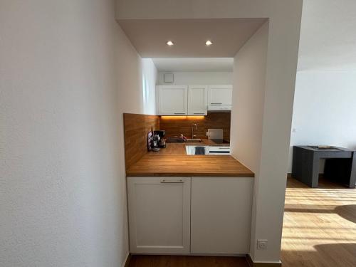 a kitchen with white cabinets and a wooden counter top at Location d’un Superbe appartement avec piscine in Roquebrune-sur-Argens