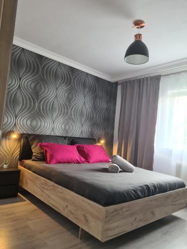um quarto com uma cama grande e almofadas cor-de-rosa em Cosy escape em Sfântu Gheorghe