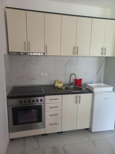 uma cozinha com armários brancos, um fogão e um lavatório em Drinsko Srce em Ljubovija