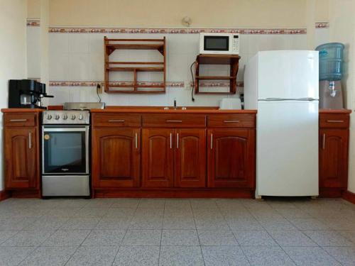 cocina con armarios de madera y nevera blanca en Casa Xelaju Apartments, en Quetzaltenango