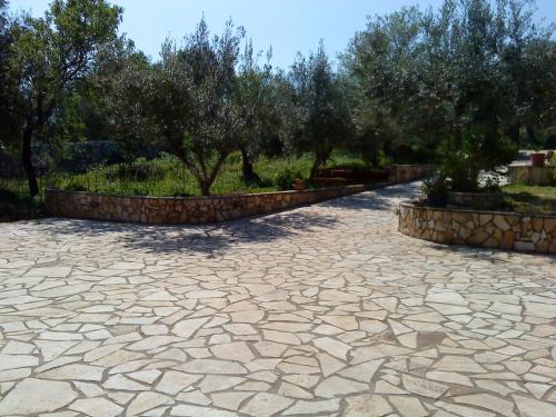 een stenen patio met bomen op de achtergrond bij Villa Eleftheria in Karavomylos