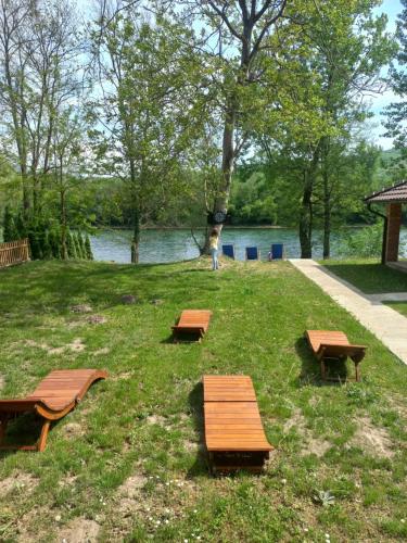 three benches sitting in the grass next to a lake at Drinsko Srce in Ljubovija