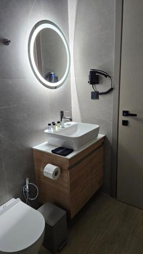 a bathroom with a sink and a toilet and a mirror at Sezame ApartHotel in Ioannina