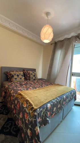 een slaapkamer met een bed met een bloemdekbed bij 2 Bedrooms 1 Bathrooms-2 Pools&With Direct beach Access in Tanger