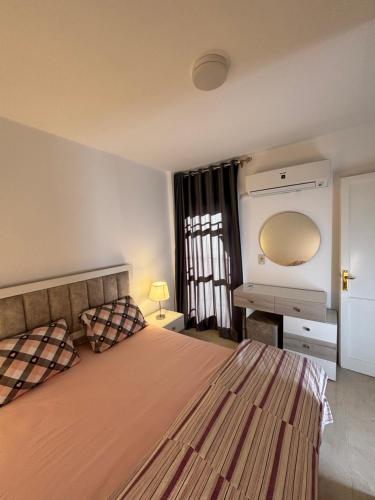 1 dormitorio con 1 cama y TV en la pared en Luxury Inn:2BR Amazing Garden View in Madinaty B10, en Madinaty