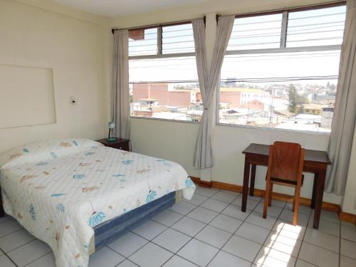 Casa Xelaju Apartments في كويتزالتنانغو: غرفة نوم بسرير ومكتب ونافذة