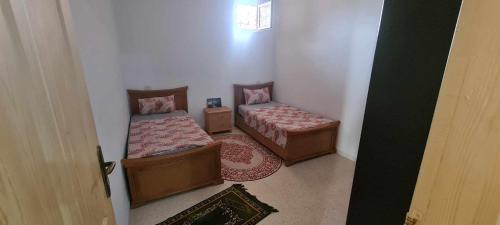 a small room with two beds and a door at Résidence karim mami in Gabès