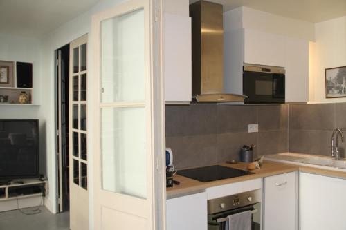 Il comprend une cuisine avec des placards blancs, un évier et une télévision. dans l'établissement Blois La Tour 1696, à Blois