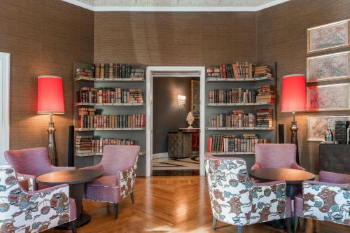 a library with chairs and book shelves with books at Hotel Palacio del Retiro, Autograph Collection in Madrid