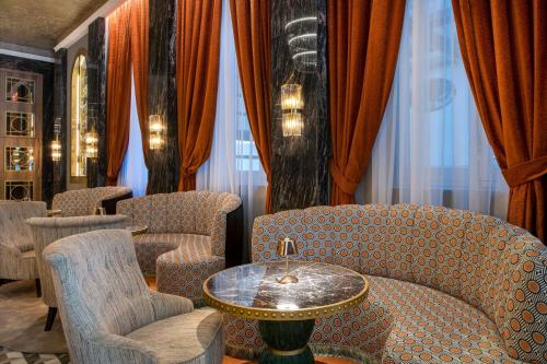 a waiting room with chairs and a table and curtains at Hotel Palacio del Retiro, Autograph Collection in Madrid