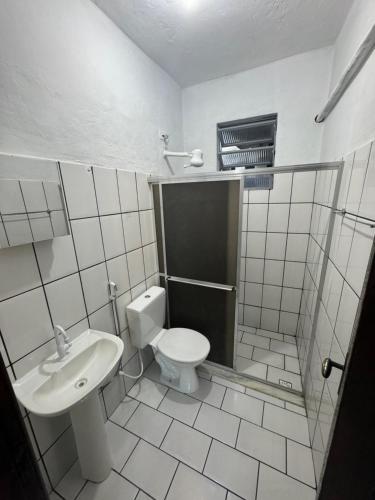 a white bathroom with a toilet and a sink at Casa Bela Vista in Angra dos Reis
