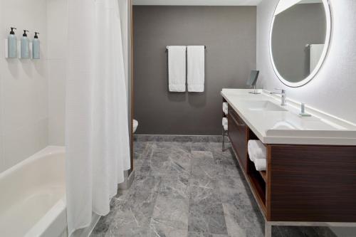 拉瓦尔Courtyard by Marriott Montreal Laval的带水槽、浴缸和镜子的浴室