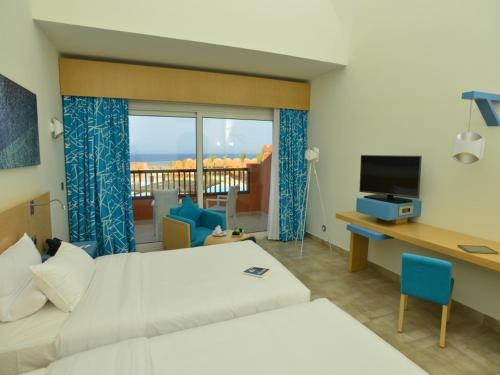 a hotel room with a bed and a desk and a window at Novotel Marsa Alam Beach Resort in Quseir