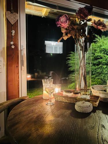 a table with two glasses and a vase with flowers at Kuća Šuma in Velika Buna