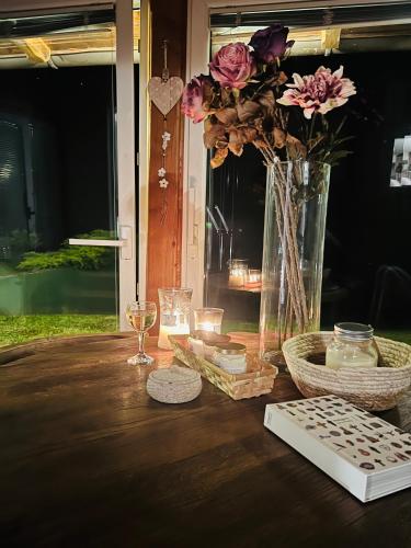 a wooden table with a vase with flowers and candles at Kuća Šuma in Velika Buna