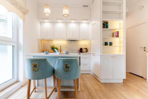 a kitchen with white cabinets and blue bar stools at FoRest Longinówka - las, jezioro, parking, Netflix i Prime, TV55" in Brodnica