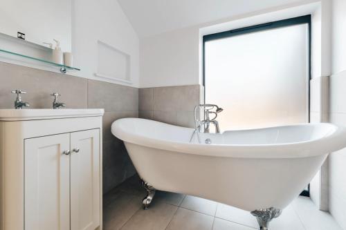 a white bathroom with a tub and a sink at The Linhay in Peterborough