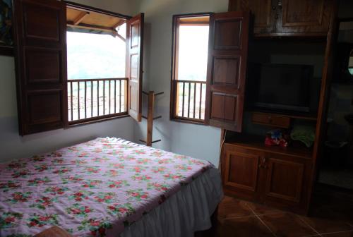 a bedroom with a bed and a tv and windows at Hotel Atenas Jericó in Jericó