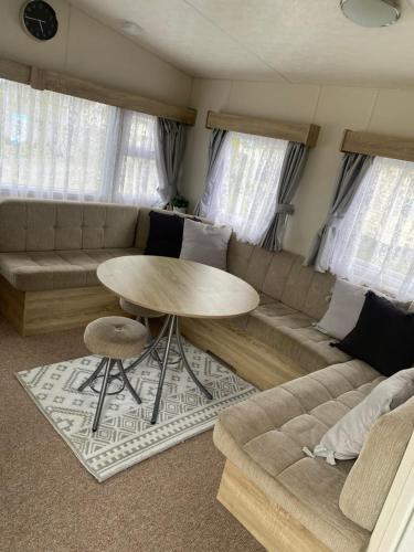 ein Wohnzimmer mit einem Sofa und einem Tisch in der Unterkunft Caravan Louise in Rhyl