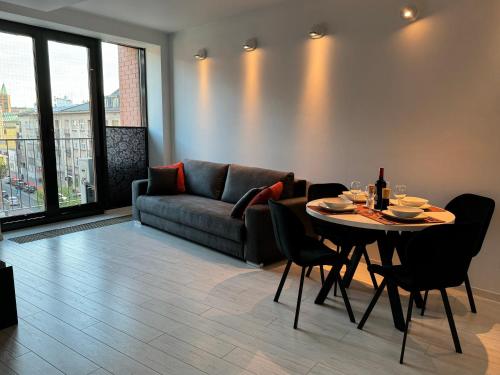 ein Wohnzimmer mit einem Sofa und einem Tisch mit Stühlen in der Unterkunft Black&White Angel Apartment in Krakau