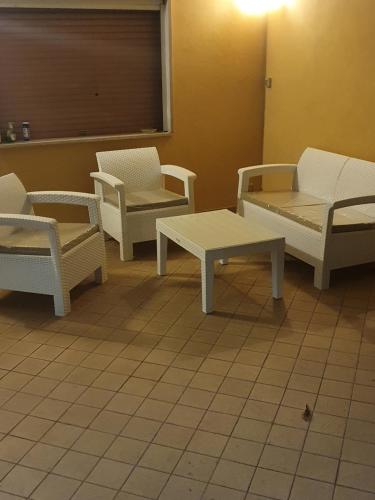 een kamer met witte stoelen en tafels en een raam bij B&B Paradiso in Paganica