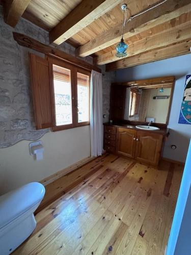 a room with a wooden floor and a bathroom with a sink at Solpostada_Casa de pueblo reformada in Pobla de Masaluca