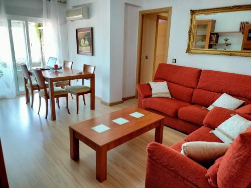 ein Wohnzimmer mit einem roten Sofa und einem Tisch in der Unterkunft Apartamento Deluxe El Camino in Alcalá de Henares